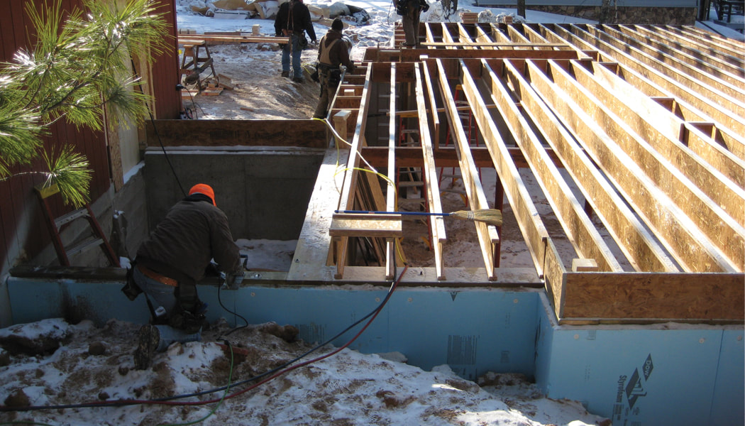 Builder preparing a foundation to receive the post and beam frame